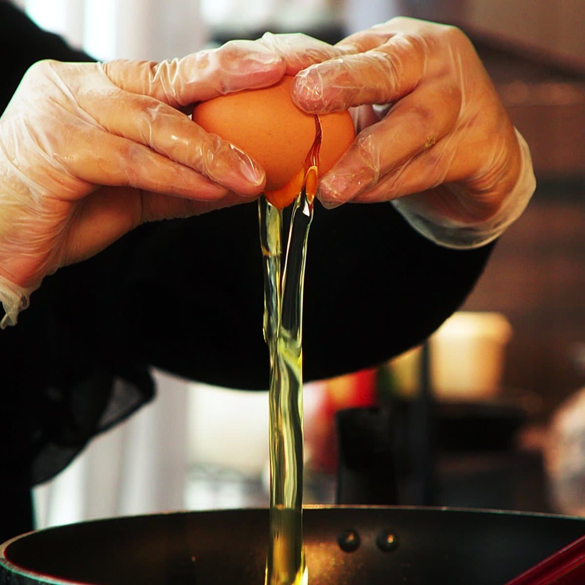 An egg being cracked into a pan at Egg & Co