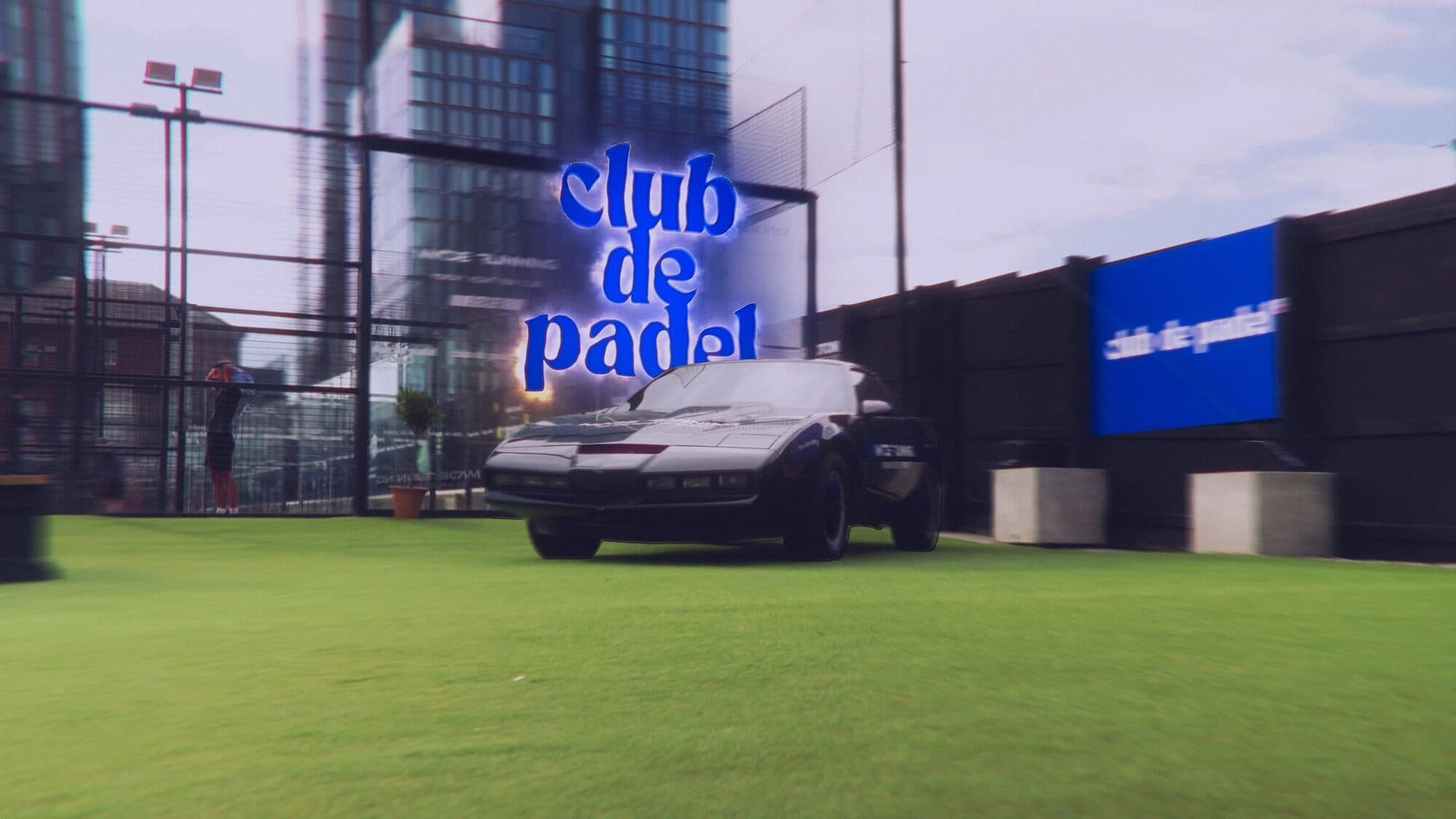 The glowing Club de Padel sign above a black sports car on the club's lawn